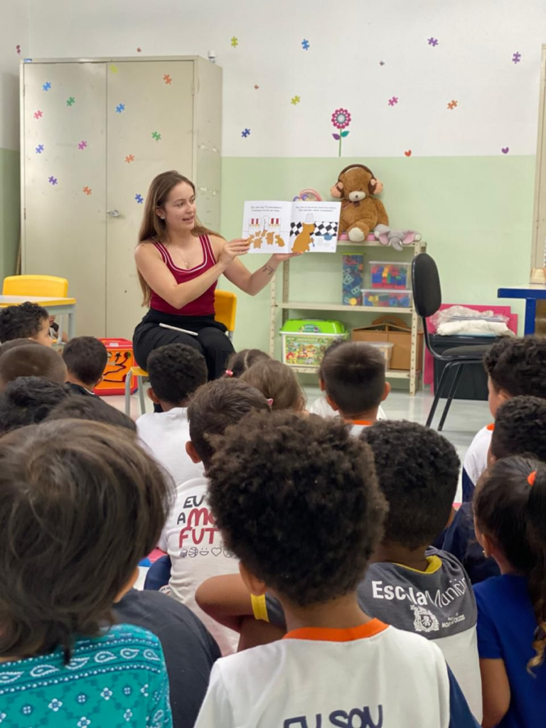 A educadora mostra o livro com as capivarinhas para os alunos