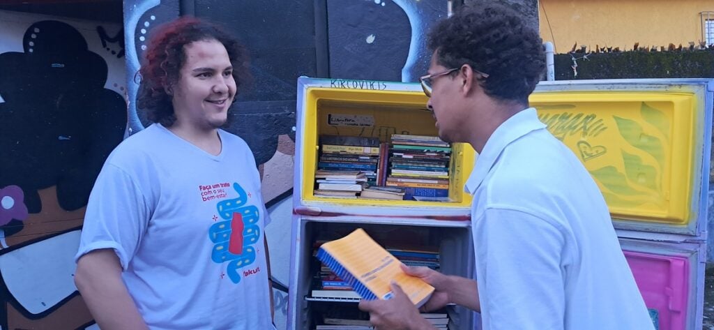 Douglas (à esquerda) abastece a biblioteca com ajuda de moradores